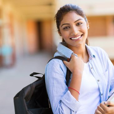 Young, smiling female student with a backpack and notebooks. 