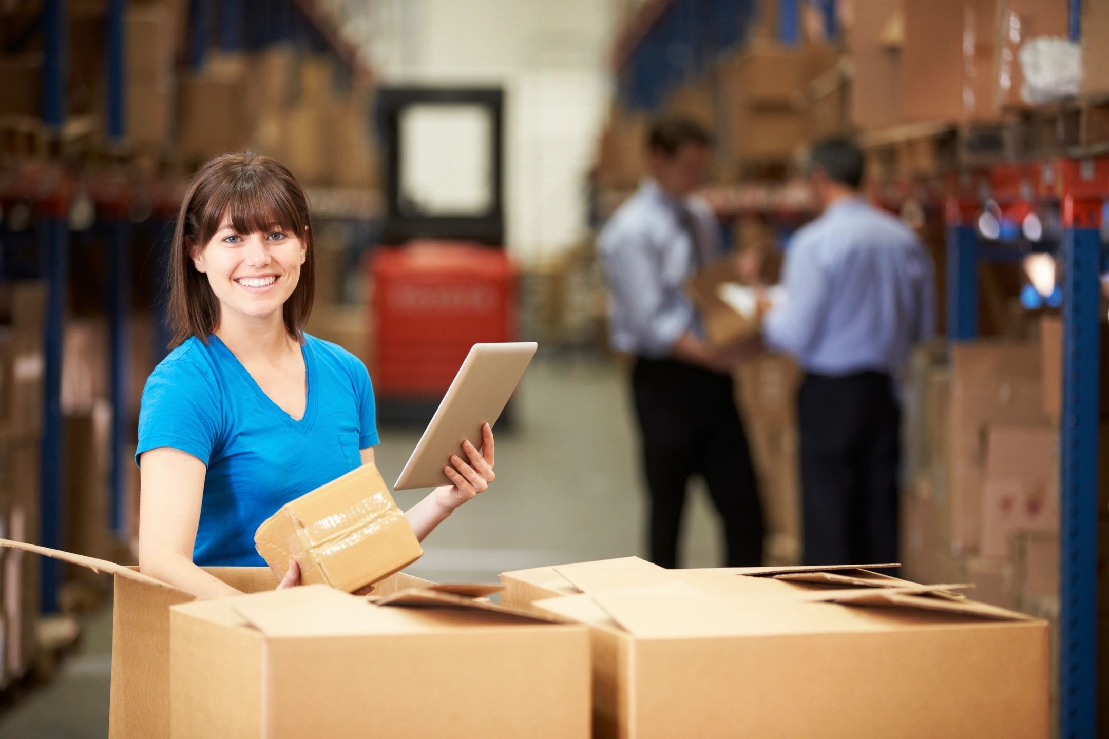 Warehouse worker manages inventory with a digital tablet in a busy distribution center.