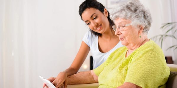 carer and old woman looking at an ipad
