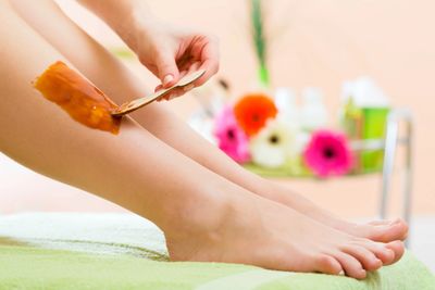 Lady with wax being applied to her lower leg before her hair removal treatment 