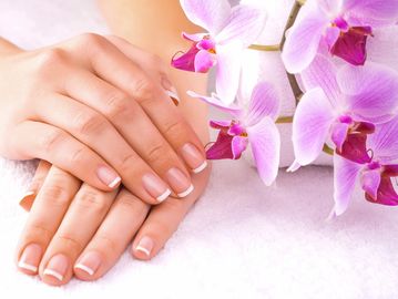 A pair of hands on a cloth with orchids next to them.