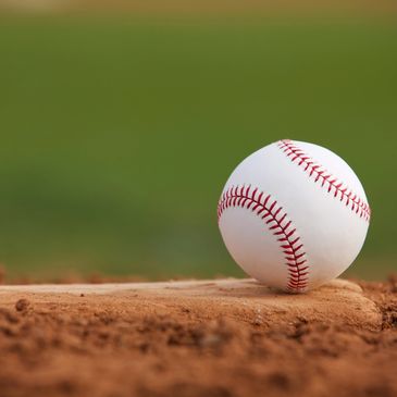 Close up of baseball sitting in dirt.