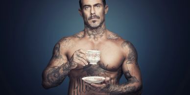 Sexy tattooed man drinking tea