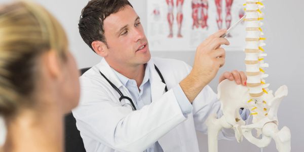 The doctor is pinpointing where the patient has interference in her spine causing her pain.