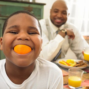 smiling young boy with orange slice in mouth
