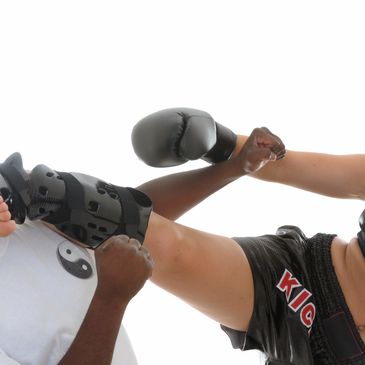 A woman kick boxer kicking a persons face