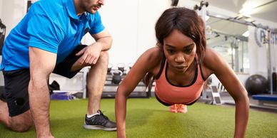 personal trainer with fitness enthusiast doing press ups