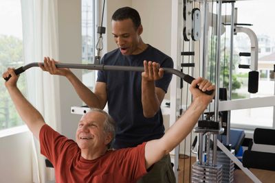 A trainer helping an old man workout