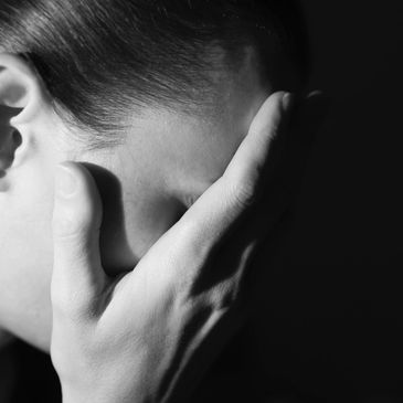 A black and white picture of a women with her hand on her face with a headache. 
