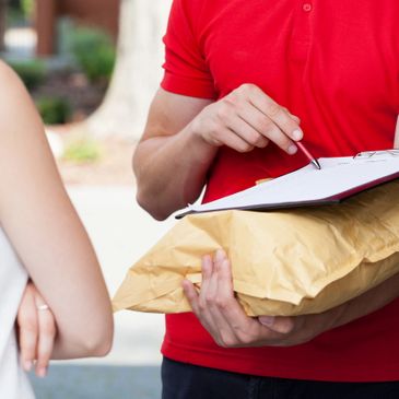 A person is holding a package pointing to the paperwork with a pen in front of a customer