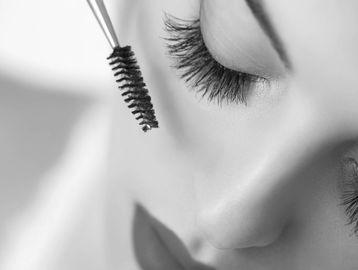 Woman with eyelash extensions and red lips with a mascara wand