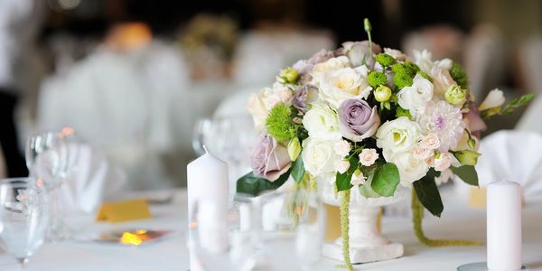 tavolo con tovaglia bianca e candele con boquet di fiori al centro tavola