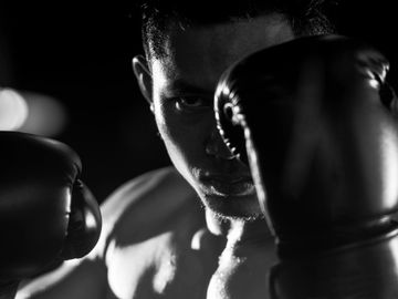 A black and white image of a boxer peering through a high guard