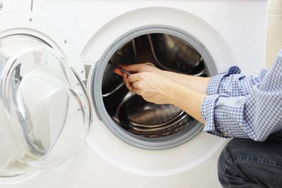 A person working on a washing machine with an open door.