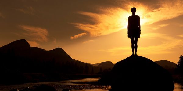 A silhouette of a man standing at a rock