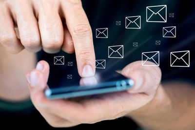 Image of hands and smart phone being used to send e-mail