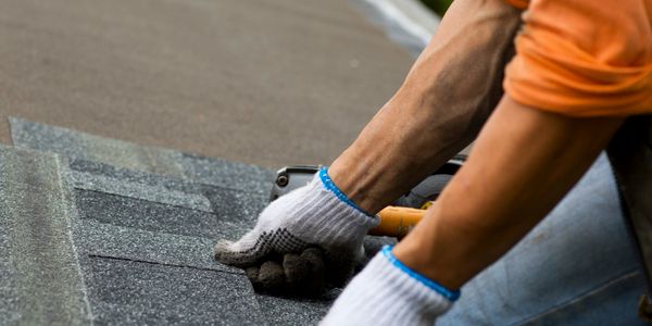 Stock photo of a roofer installing asphalt shingles.