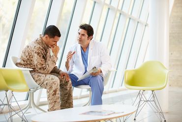 color photo of a man in military uniform listening to a doctor