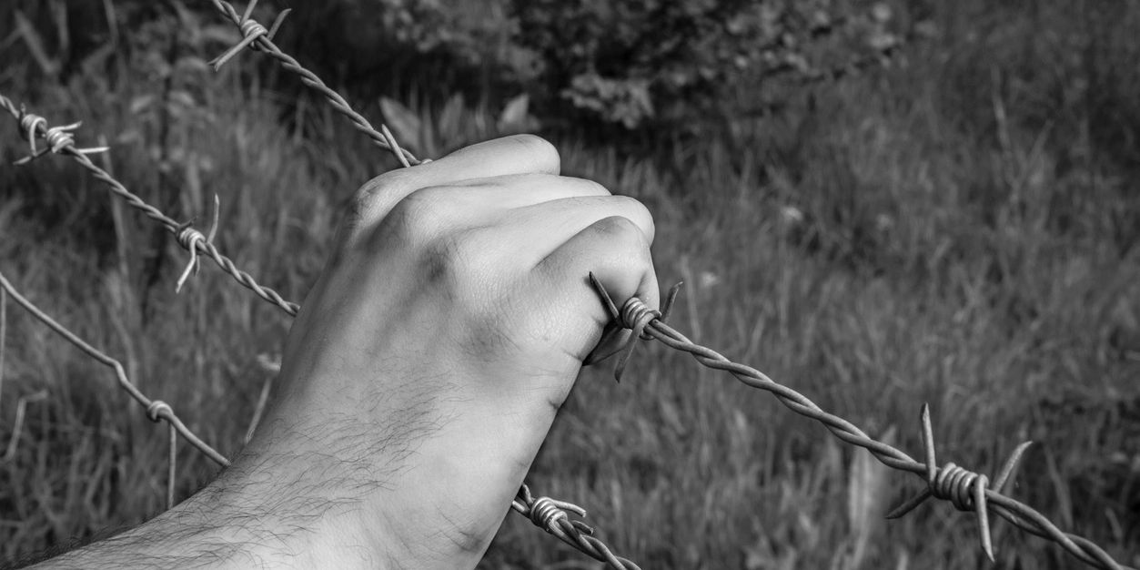 Hand pulling away barbed wire fencing