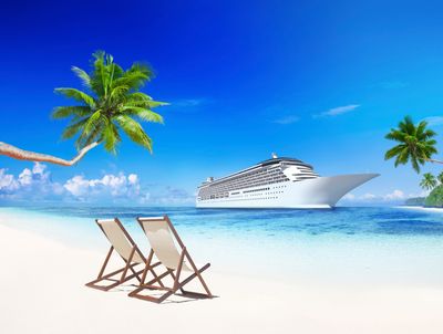 White sandy beach with palm trees and a cruise ship in the distance that a travel agent booked.