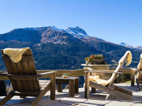 Wooden patio furniture in front of a mountain scene