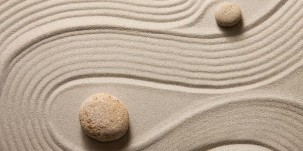 Zwei Steine auf Sand verdeutlichen die Harmonie, die man im Leben anstrebt.