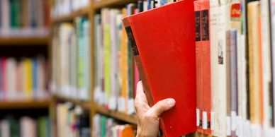 Person pulling a book from a shelf