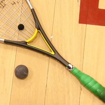 Squash racquet and squash ball on a court floor