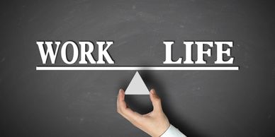 A hand holding a triangle with the words "Work" and "Life" to show that they are balanced.