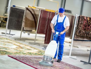 Person cleaning carpets and rugs with carpet shampoo machine