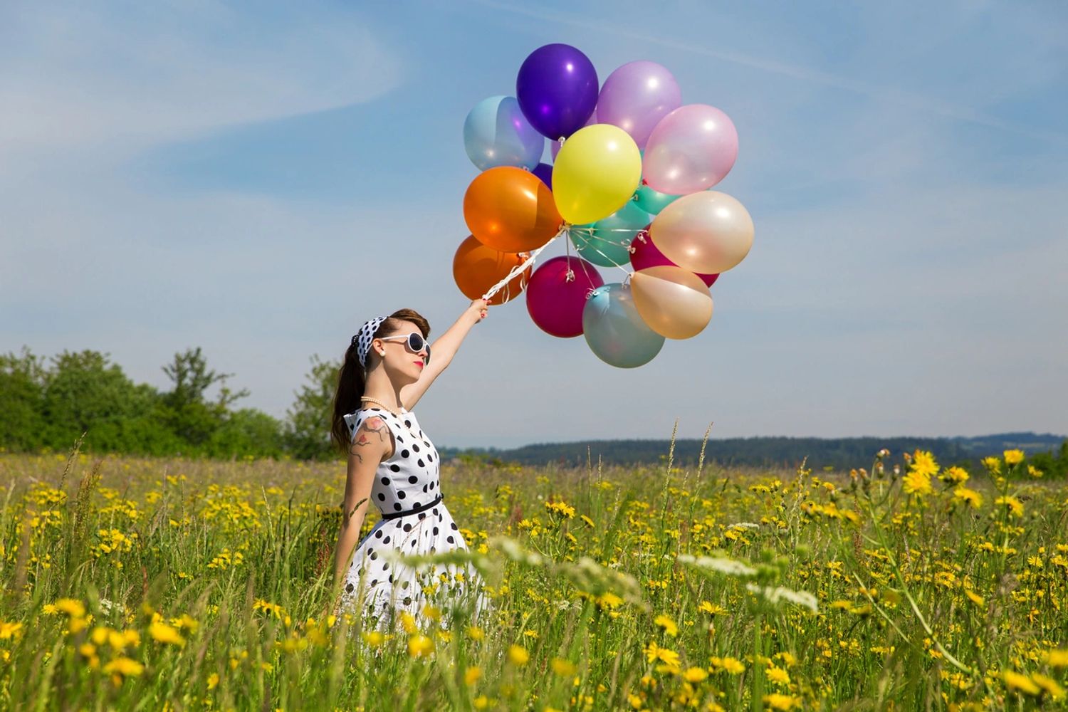 Woman walking through a field with balloons feeling free and happy holistically healthy and balanced