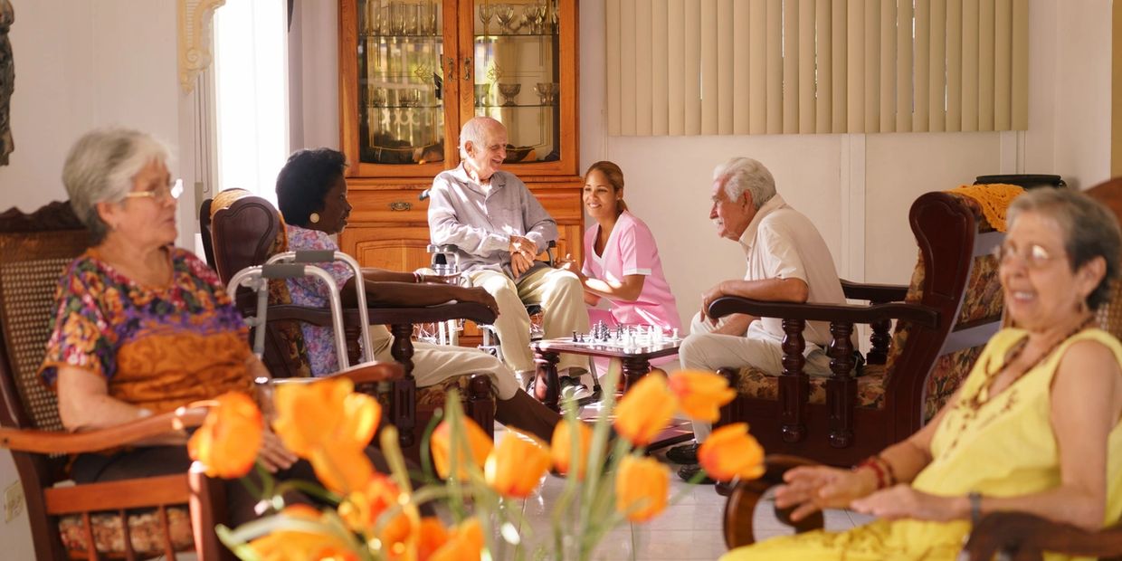 Group of elders in large living room at a residential facility. 