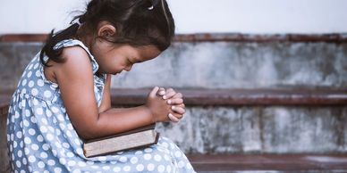 Little Girl praying over a Bible on steps