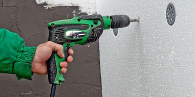 A person drilling in a wall with driller