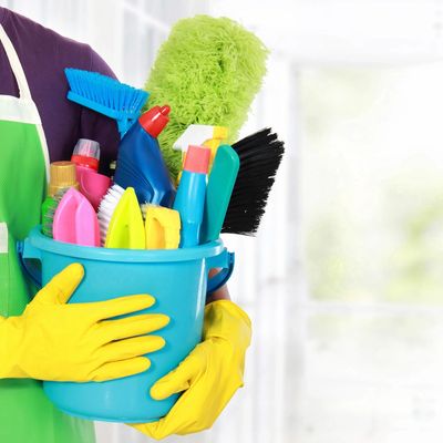 Trained house keeping holding a bucket with eco-friendly cleaning products and brushes.