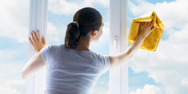 woman washing a window with a yellow rag