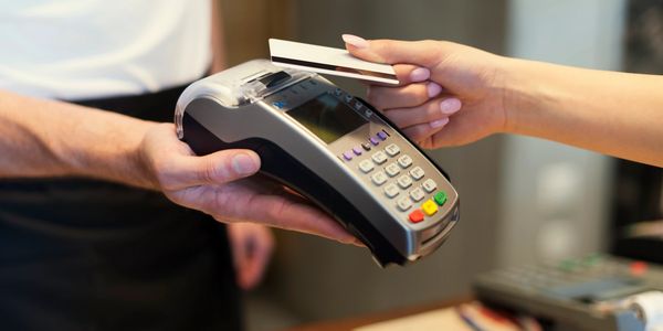 Merchant holding a mobile credit card reader while customer presents a card. 