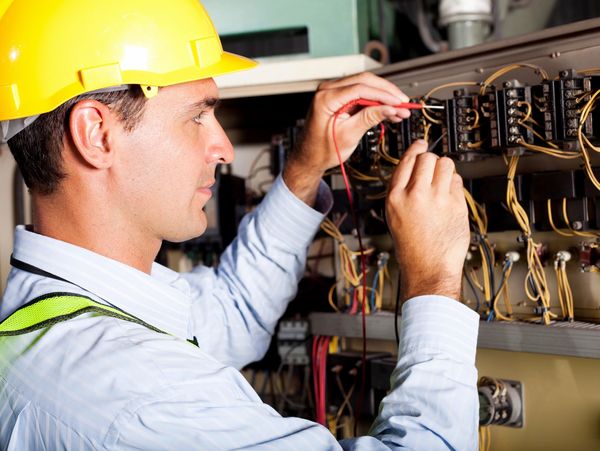 nice cheerful electrician repairing electrical panel
