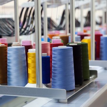 Embroidery threads in a variety of colours attached to several machine embroidery machines.