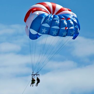 two people parasailing with an american flag sail 