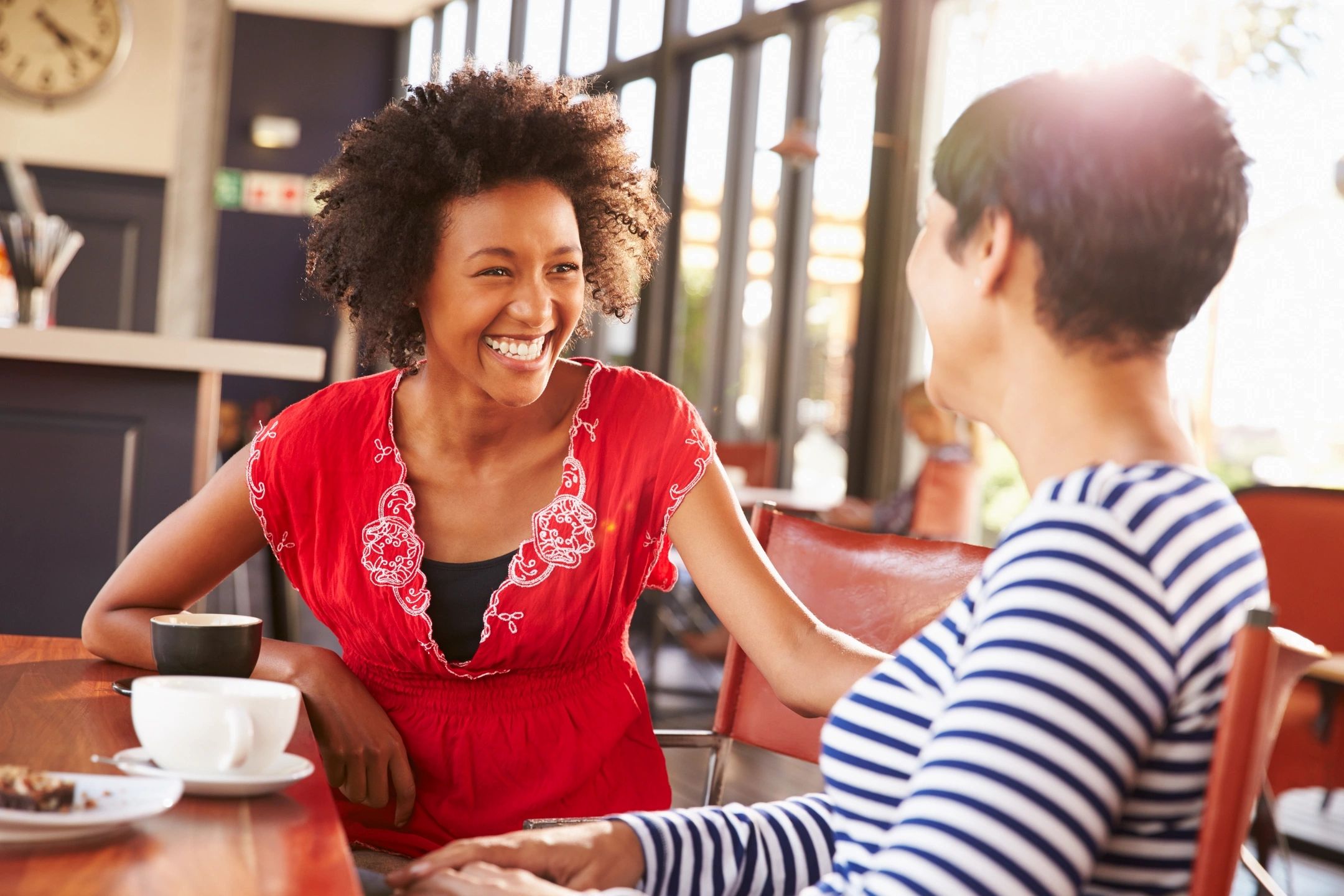 two women laughing together at a cafe
