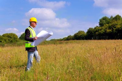 Man with construction hat reviewing natural site for development.