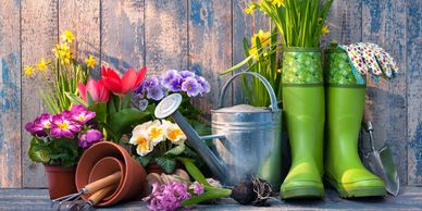 gardening tools with watering can and boots against whitewashed blue fence
