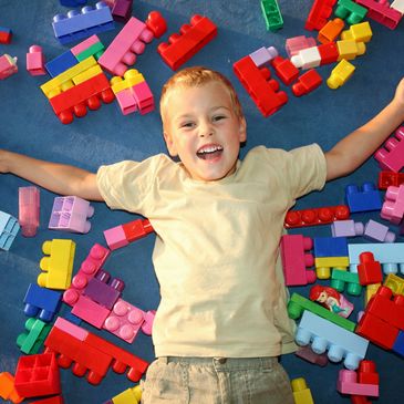 Happy kid lying with the colorful blocks.