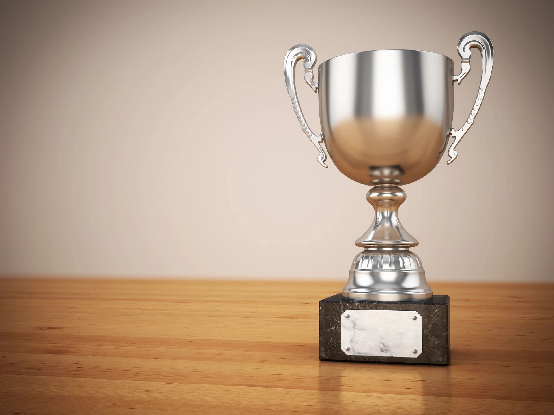 Silver trophy cup on woodgrain desktop