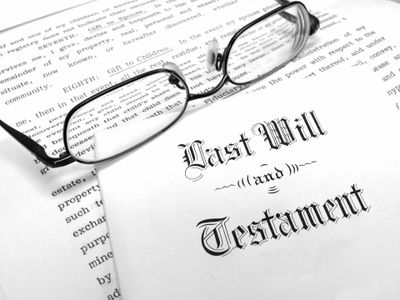 pair of glasses laying on a document titled "last will and testament" in gothic caligraphy