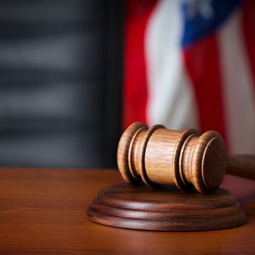 Generic photo of gavel on desk with American flag in background.