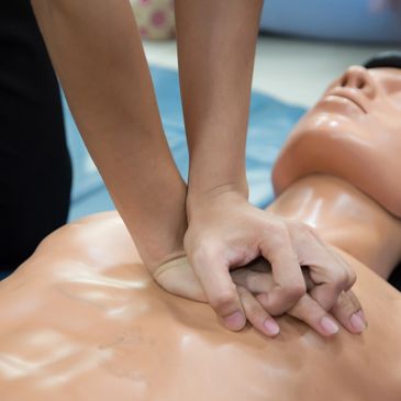 Demonstrating proper hand placement on a manikin during chest compressions for CPR skills session.