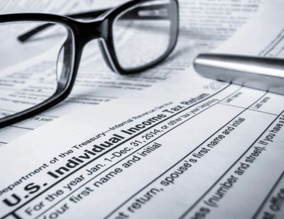black pair of glasses laying on top of an us income tax return.