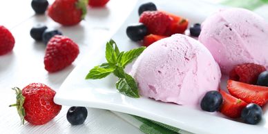sorbet with strawberries, blueberries and mint on white plate with green checkered napkin
